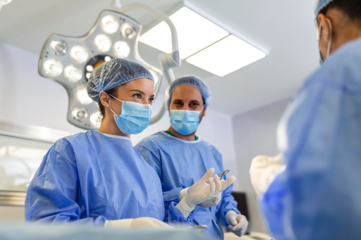 Portrait of team of multiethnic surgeons at work in a operation theatre. Several doctors surrounding patient on operation table during their work. Team surgeons at work in operating room. Cirugía General y Aparato Digestivo